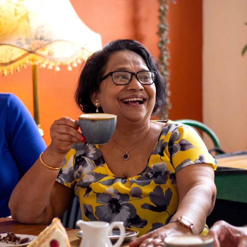 older lady holding a cup of tea in celebration